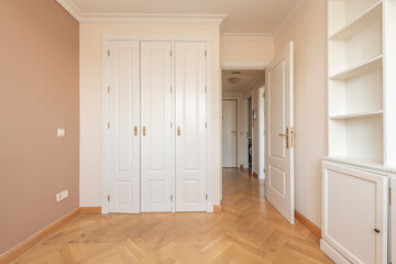 bedroom with white lacquered wooden bookcase along with built-in wardrobe and front door