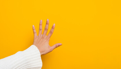 female hand making a prohibition and stop sign lonely on a yellow background