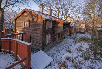 Old log houses with apartments and stores in a park a winter day afternoon in Stockholm