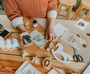 Young woman putting a stamp on a linen bag packing purchase