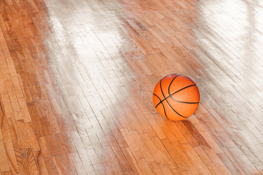 Basketball on hardwood court floor with natural lighting. Workout online concept. Horizontal sport theme poster, greeting cards, headers, website and app