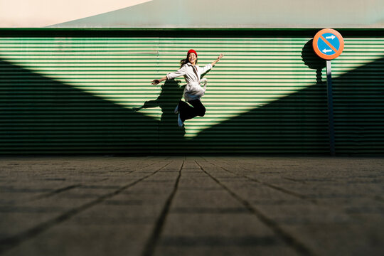 Carefree young woman jumping on footpath