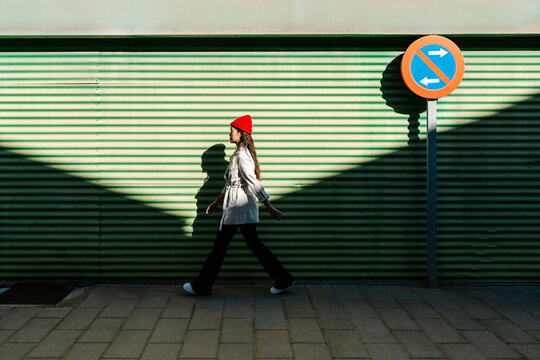 Woman wearing knit hat walking on footpath