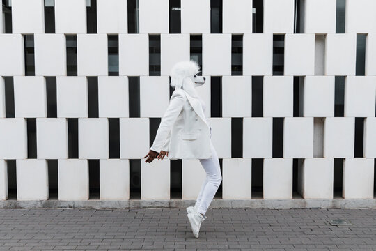 Woman wearing dog mask dancing on footpath