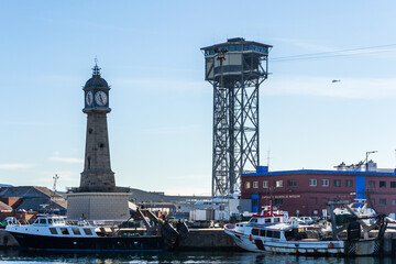 Fototapeta na wymiar The cable car tower and clock tower overlooking the harbour at Port Vell, Barcelona, Spain.
