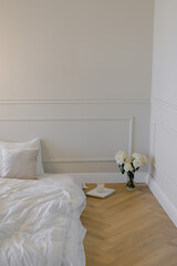 Bed with white linens and pillows Minimalistic interior White roses in a vase