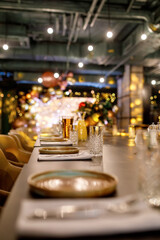 festive table with dining utensils, decorated with New Year's table composition against the background of the restaurant hall in blur