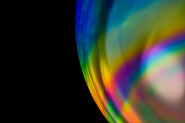 Close-up soap bubble, like rainbow spectrum reflection from lens on dark background. Abstract...