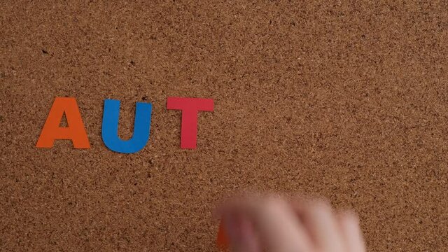 A child placing the letters of the word Autism onto a cork board. Autism spectrum disorder.