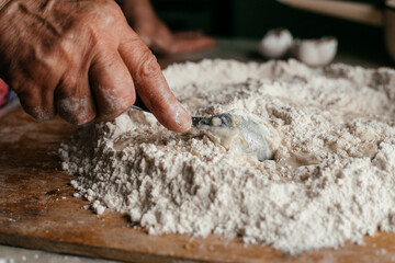 close-up of hands kneading dough with a spoon on the table in their home kitchen