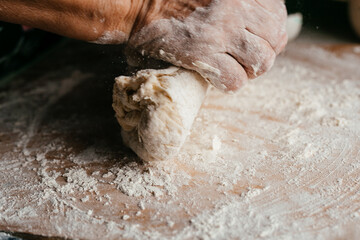 hands close-up kneading dough on a wooden board