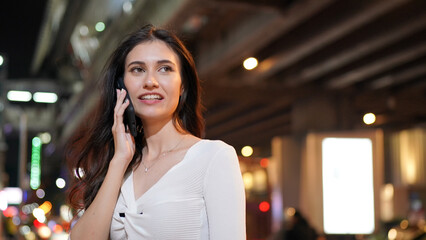 Close up Young Woman Talking to Someone on her Mobile Phone While Looking Into the Distance with Happy Facial Expression.