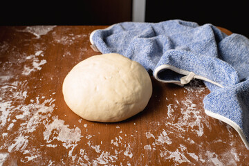 The finished kneaded round dough lies on the kitchen table at home.