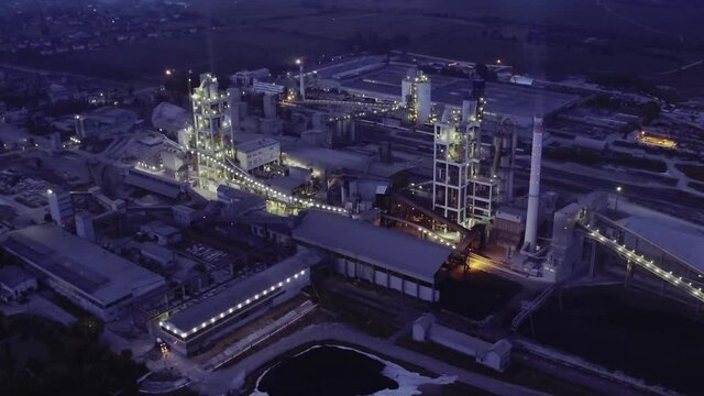Industrial cement factory at night. Factories and production plants at dusk. Industrial area, electricity power supply substation. Manufacturing products. Power electric plant