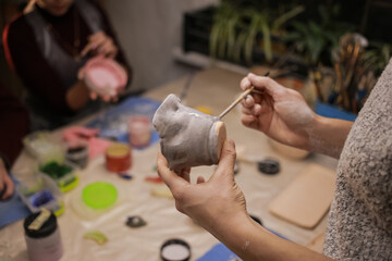 A human sculptor makes a clay product with his own hands