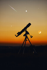 Silhouette of telescope and countryside under the starry skies.