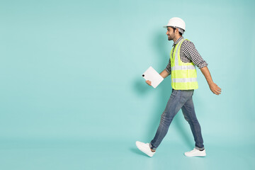 Full length portrait of young professional heavy industry engineer or worker walking and holding tablet Computer isolated on green background, Side view - 477342055