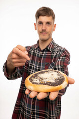 Young handsome tall slim white man with brown hair holding kolach in front of him pointing at it isolated on white background