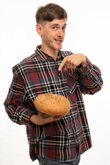 Young handsome tall slim white man with brown hair pointing at loaf of bread smiling in flannel shirt isolated on white background