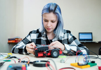 School students making robotic cars. Teenager girl at robotics school makes robot managed from the...