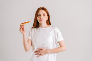 Studio portrait of sick sad young woman feeling pain in stomach after eating pizza, suffering...