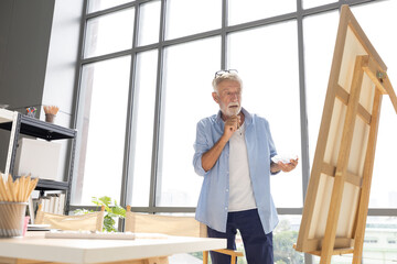 senior man painting a picture from paintbrush in free time