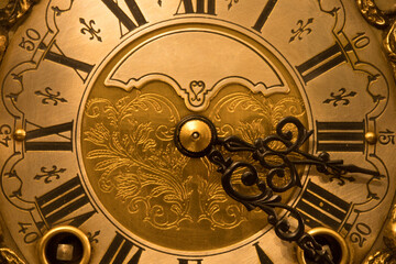 Closeup of the dial of an old wind-up table clock made in The Netherlands. Highly decorated vintage wooden clock.