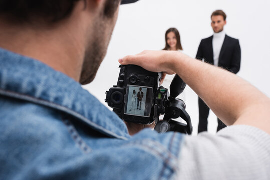 photographer with digital camera taking photo of blurred models isolated on white.