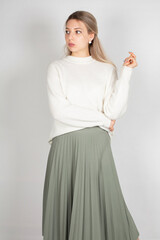 Woman with long hair and white skin isolated on grey in white sweater and olive skirt