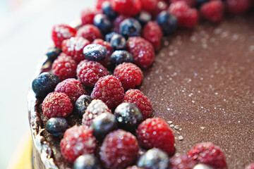 part of a round chocolate cake with fresh raspberries and blueberries