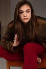 Young woman with long dark hair and brown eyes with dark grey wall behind