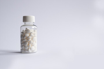 Bottle of white tablet pills on a white background with copy space. For advertising and health care messages
