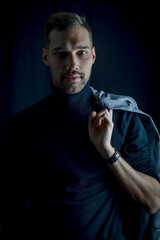 portrait of a young businessman holding his jacket over his shoulder and looking intently in front of him