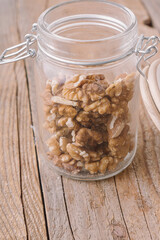 Peeled walnuts in glass jar on wooden background. Storage of nuts. Storage container at kitchen