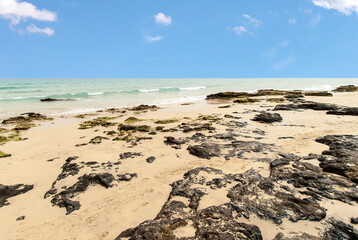 Strand mit Felsen unterm Sand an einem sonnigen Tag