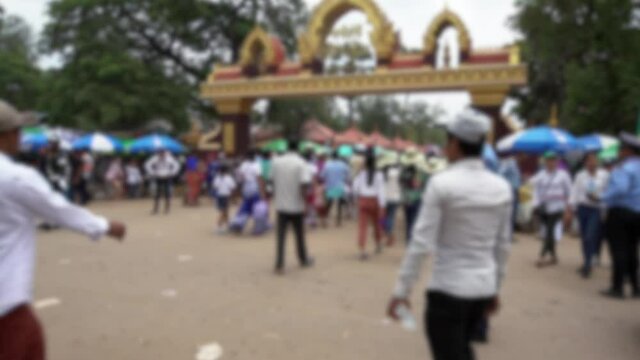 Blurred defocused view of policeman is controling traffic jam in street with people walking inside of traditional gate at Angkor Sankranta. Cop officer at New Year celebrations