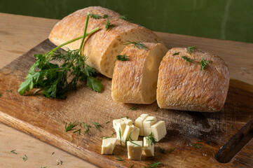 Fresh bread sliced. Dill, parsley and hard cheese. Baguette and cheese with herbs.