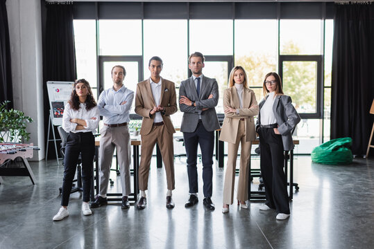 young multiethnic business people looking at camera while standing together in modern office.