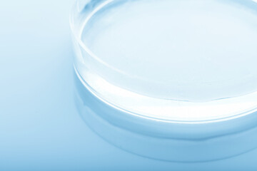 Medicine concept. Petri dish with transparent liquid on glossy laboratory table background with copy space. Analysis, chemical experiment equipment. Blue gradient map filter. Shallow depth of field