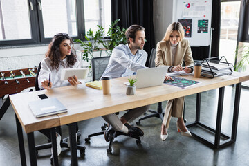 businessman pointing at analytics while working in office with businesswomen.