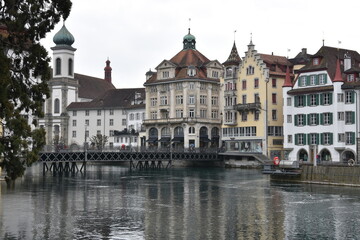 Fototapeta na wymiar Jesuit church and other historic buildings on the bank of river Reuss in Luzern. View from the opposite riverbank. 