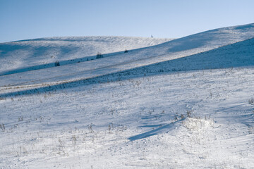 White snowy field with hills under a bright clear winter blue sky,