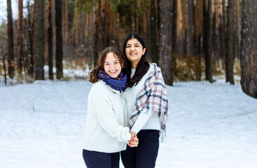 Fototapeta na wymiar Winter, two girls hug each other against the backdrop of a winter forest, cold, snow, fun.