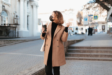 Fototapeta premium Millennial woman in mask with coffee to go