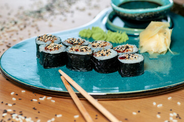 sushi rolls maki on a blue curly plate with ginger ouse and wasabi close-up

