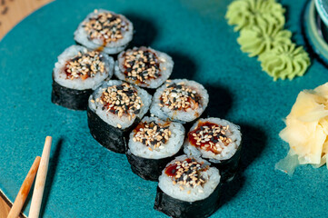 sushi rolls maki on a blue curly plate with oous ginger and wasabi
