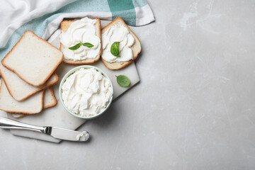Fresh bread and delicious cream cheese on grey table, flat lay. Space for text