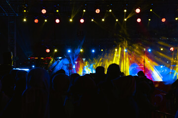 Concert background. Spotlights on the stage and silhouette of people in concert