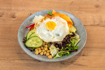 Power salad with black beans, kale, chickpeas, fried egg and cucumbers and carrots with avocado and cooked white rice