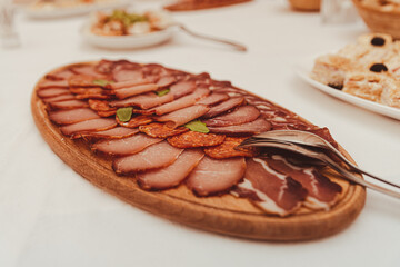 Smoked meat cut thin and served on a wooden plate